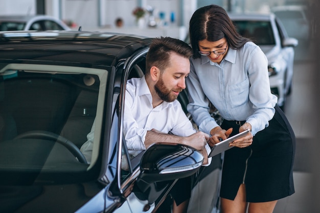 Salesman and woman looking for a car in a car showroom