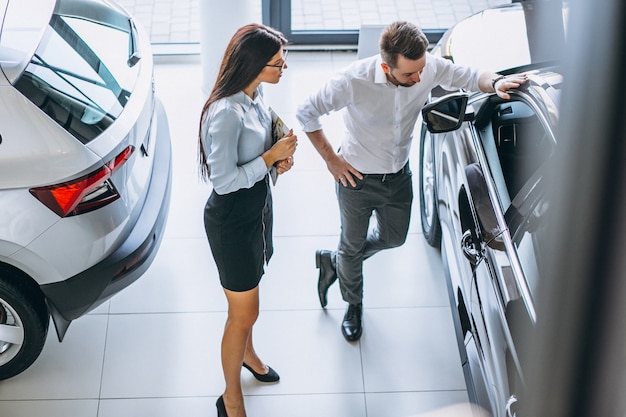 Salesman and woman looking for a car in a car showroom