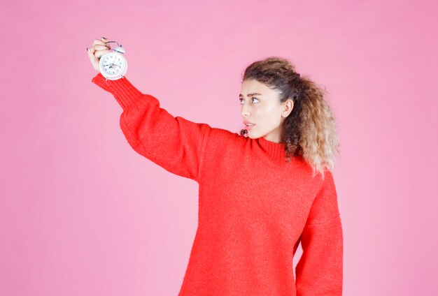 Free Photo a saleswoman holding and promoting new alarm clock.