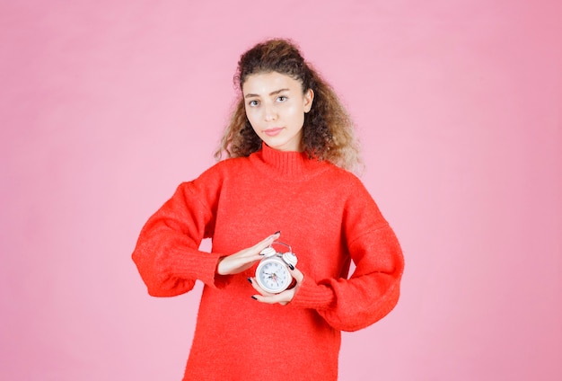 Free photo a saleswoman holding and promoting new alarm clock.