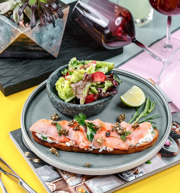 Free photo salmon sandwich with vegetables in the plate