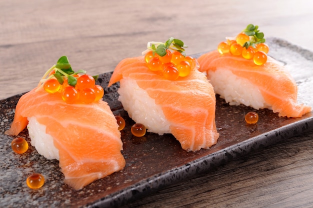 Salmon sushi with caviar on black plate