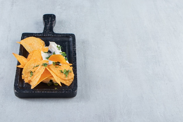 Free Photo salted crispy chips and fresh yoghurt on black cutting board.