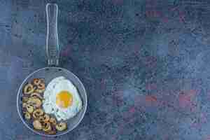 Free photo salted and spiced fried egg with parsley on a frying pan .