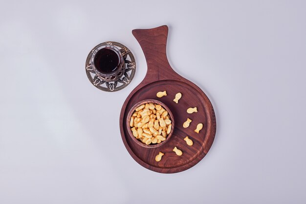 Salty crackers in a wooden cup with a glass of tea, top view.