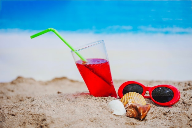 Free photo sand with drink, sunglasses and seashells