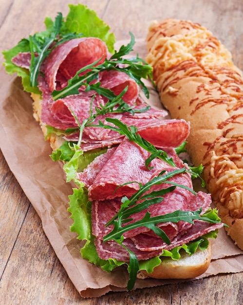 Free photo sandwich with salami, lettuce, tomato and arugula