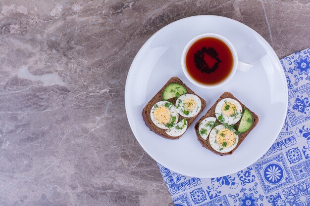 Sandwiches with boiled eggs and herbs with a cup of tea.