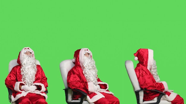 Free Photo santa claus character on chair against greenscreen backdrop, cheerful person celebrating christmas eve in red costume. young adult advertising december holiday with iconic winter suit.