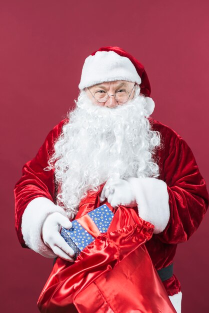 Santa Claus getting gift box from big sack