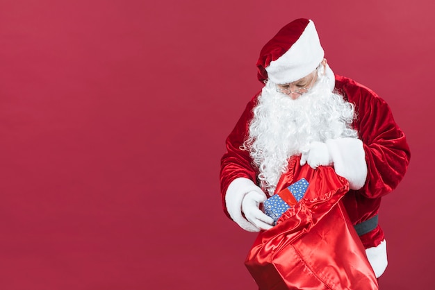 Free photo santa claus getting gift box from sack