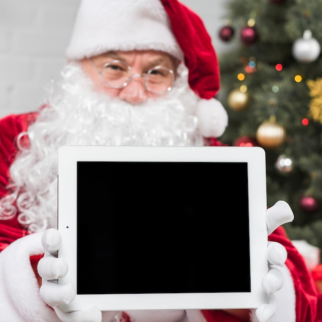 Free photo santa claus in glasses holding tablet in hands