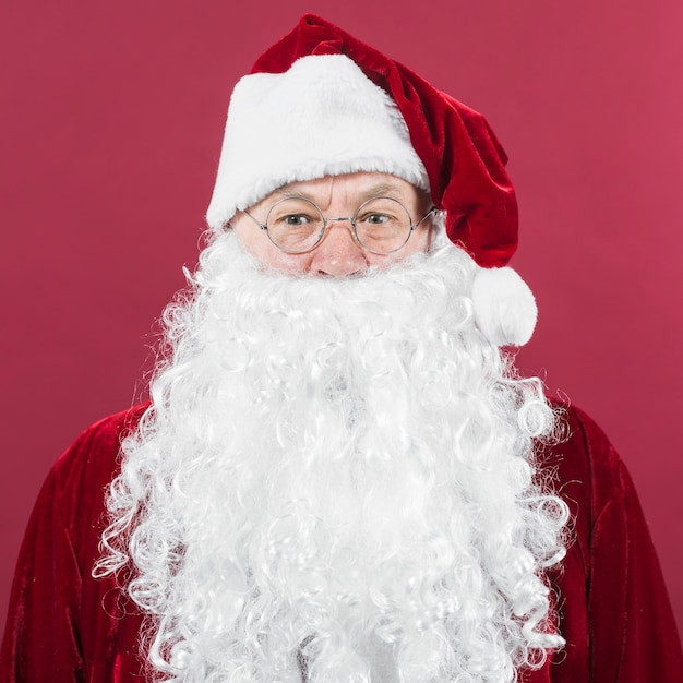 Free Photo santa claus in hat standing on red background