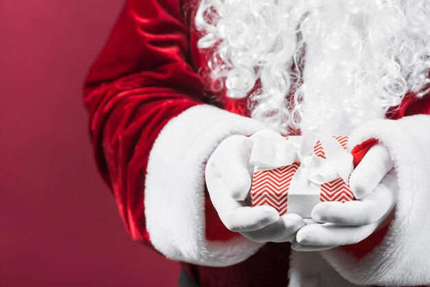 Santa Claus holding gift box with band in hands