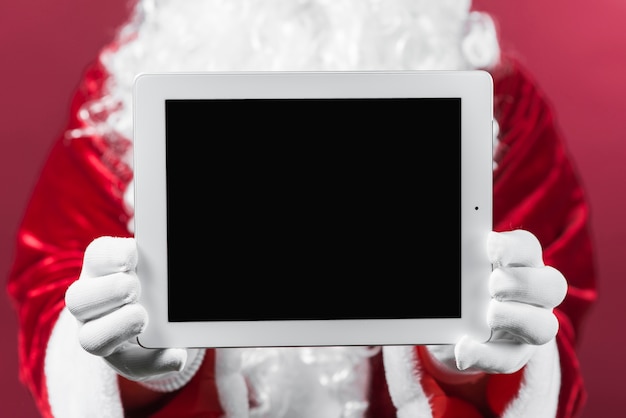 Free Photo santa claus holding tablet in hands