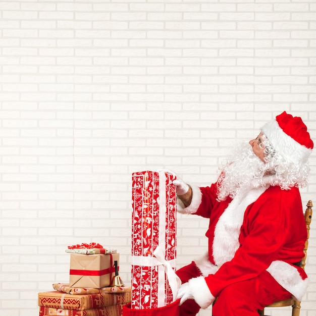 Free photo santa claus putting presents in bag