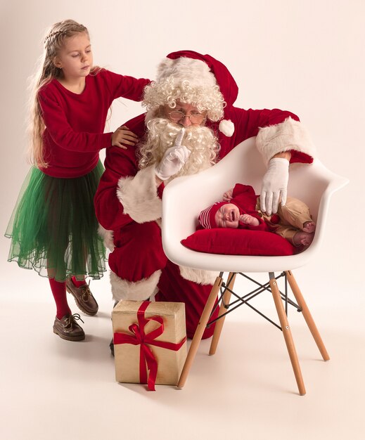 Santa Claus in red costume with a little girl and a baby isolated on white