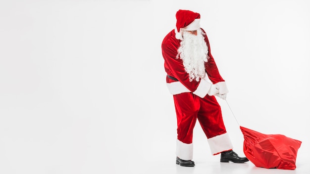 Santa Claus in red pulling sack of gifts