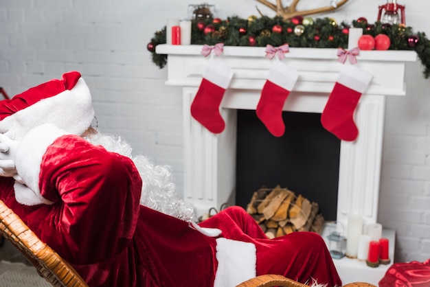 Free photo santa claus sitting on rocking chair with hands behind head