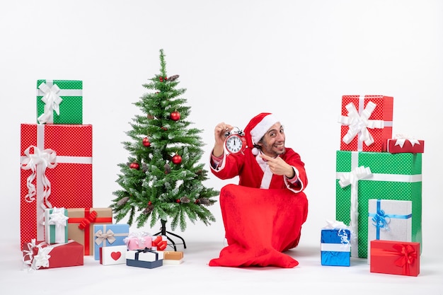 Free photo santa claus sitting with gift boxes and tree