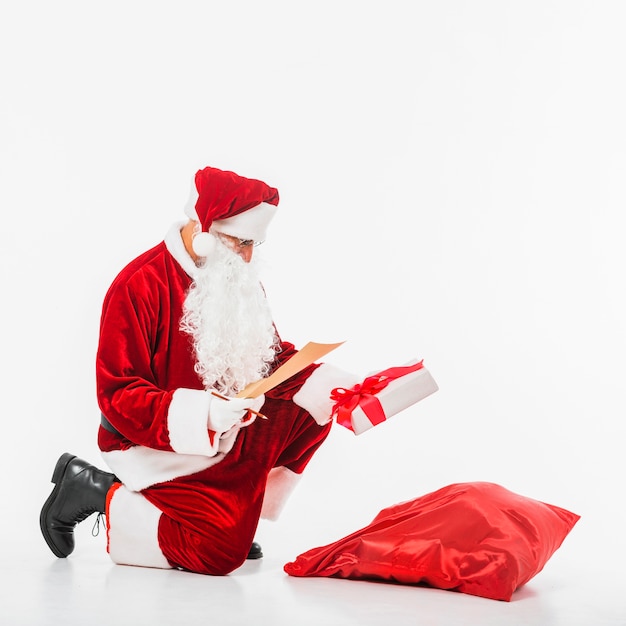 Free Photo santa claus sitting with sack of gifts and children list