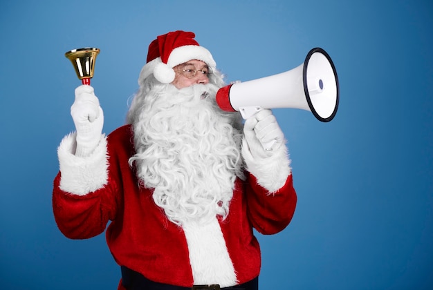 Free Photo santa claus with handbell shouting into megaphone