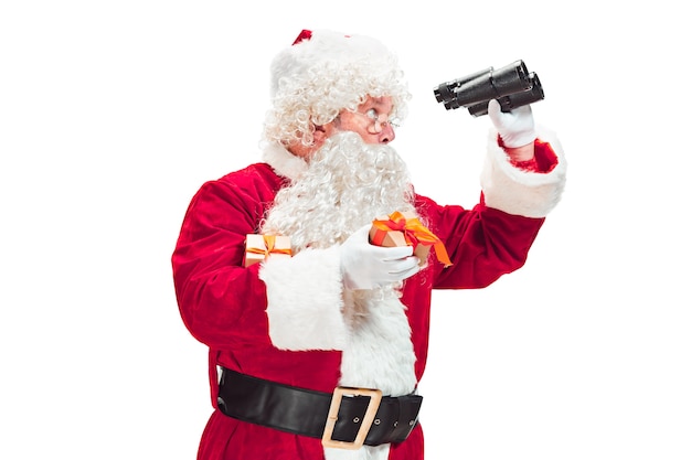 Free Photo santa claus with a luxurious white beard, santa's hat and a red costume isolated on a white background with binoculars