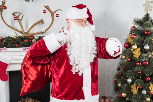 Free photo santa claus with sack checking time on wrist watch