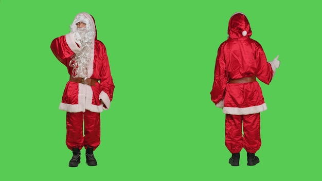 Free Photo santa gives thumbs up and thumbs down over greenscreen backdrop in studio, wearing saint nick costume. young person portraying winter main character, like and dislike gesture.