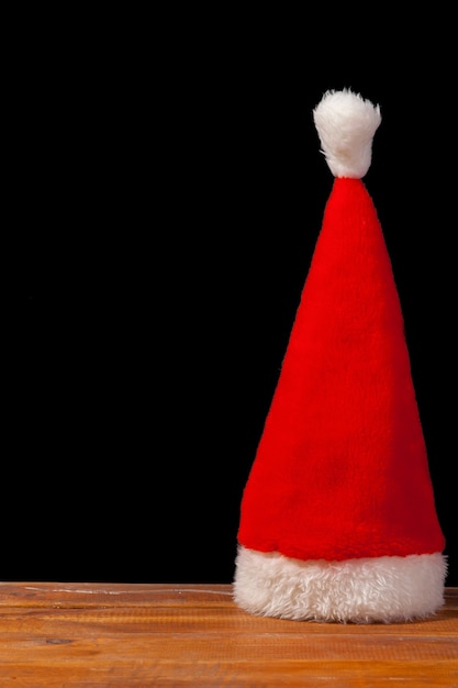 Free Photo the santa red hat on wooden table on black background