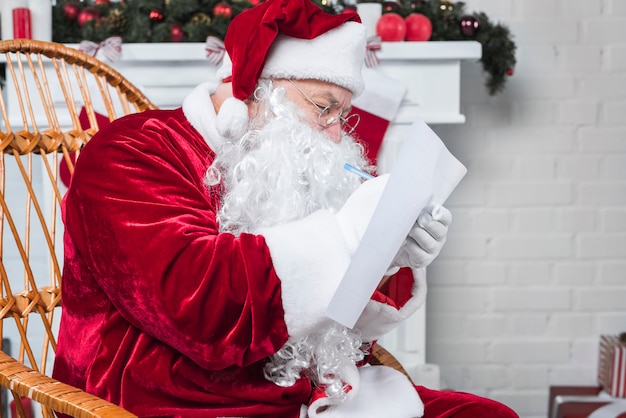 Free Photo santa sitting in chair and reading wishlist