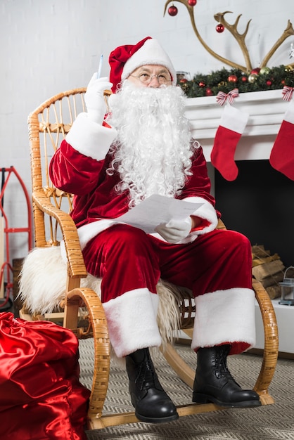 Santa sitting in rocking chair with wishlist and pen 