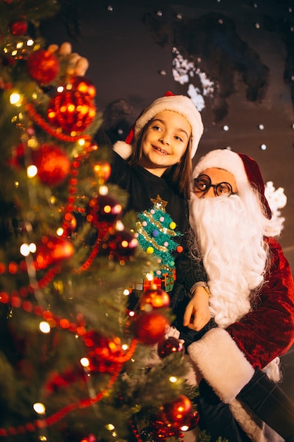 Santa with little girl decorating christmas tree together