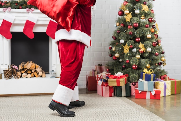 Free Photo santa with sack of gifts behind back going to christmas tree