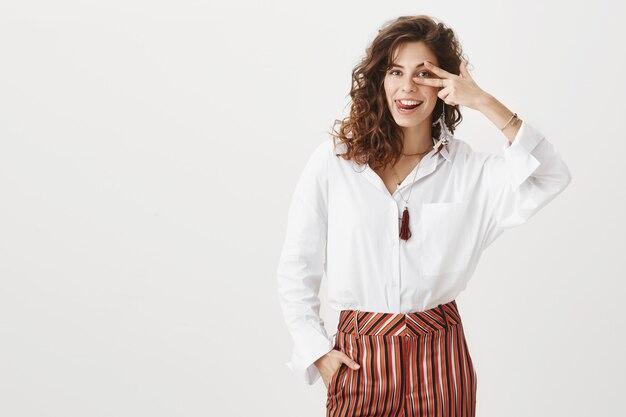 Sassy attractive businesswoman smiling and showing peace sign