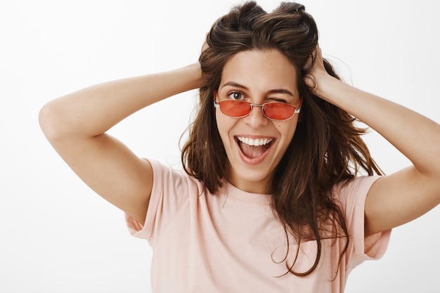 Sassy attractive girl with sunglasses posing against the white wall