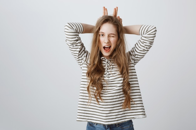 Free photo sassy pretty girl wink and showing bunny ears gesture