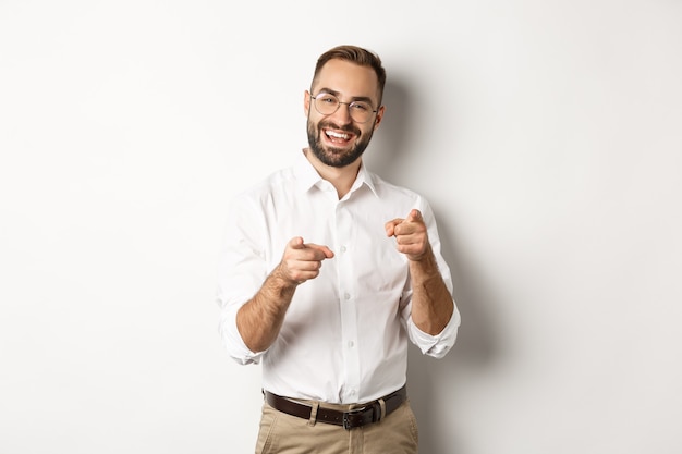 Satisfied businessman pointing fingers at camera, praising you, approve or like something, white