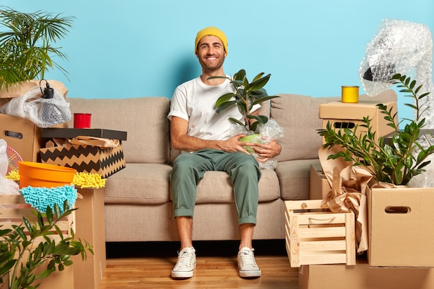 Satisfied guy poses in empty room on sofa