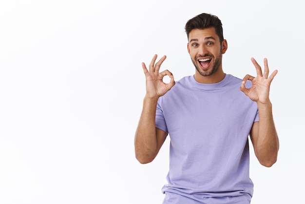 Satisfied handsome bearded millennial guy in purple tshirt showing okay gesture express delighted overjoy of good concept approve awesome idea recommend product leave positive feedback