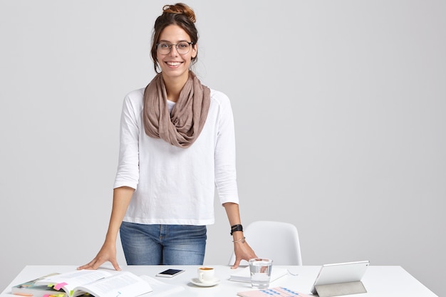 Satisfied intelligent female tutor wears white jumper and jeans