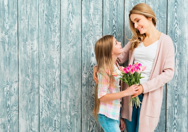 Free photo satisfied mother and daughter smiling and looking at each other