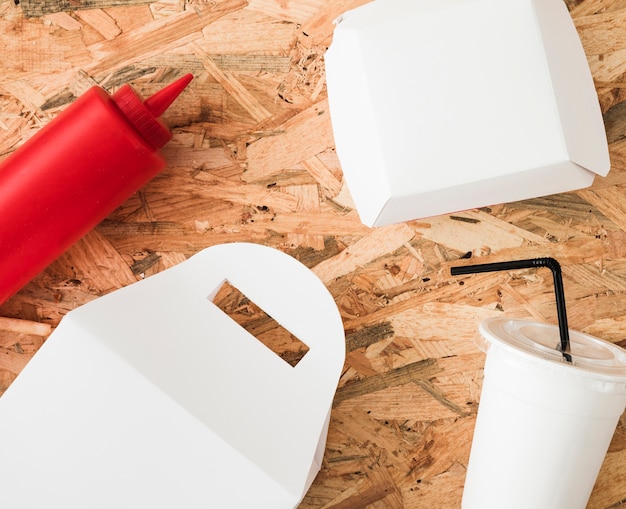 Free photo sauce bottle; white package and disposable drink on wooden backdrop