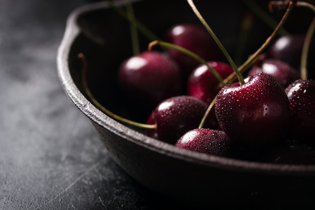 Saucepan with cherries on a black wooden table