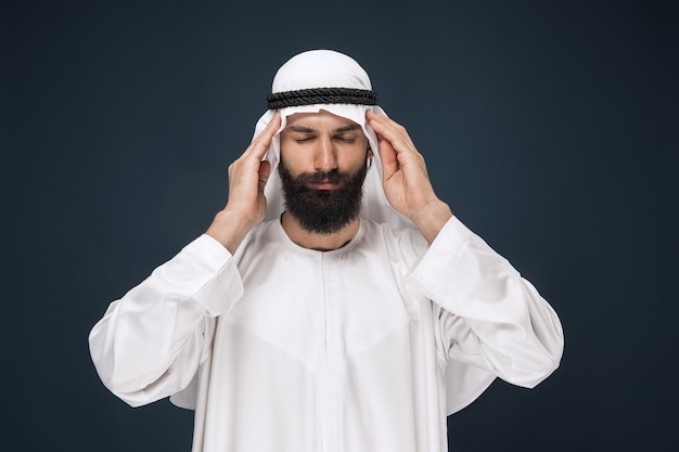 Saudi Arabian man on dark blue wall