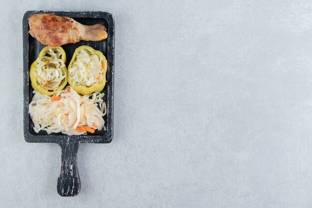 Sauerkraut and fried chicken leg on black board.  