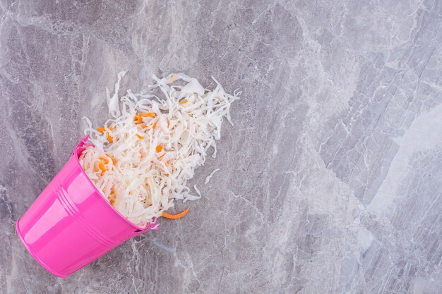 Free photo sauerkraut in a overturned bucket, on the marble.