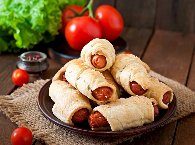 Sausage in the dough sprinkled with sesame seeds on a wooden background in rustic style