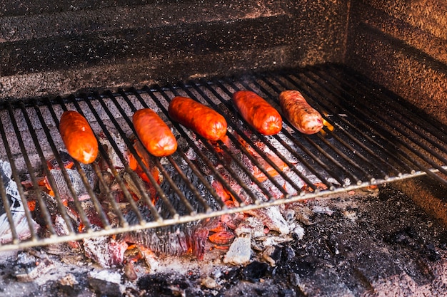 Sausages grilling over burnt coals in a portable barbecue