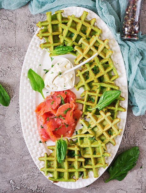 Savory waffles with spinach and cream cheese, salmon in white plate. Tasty food. Top view. Flat lay